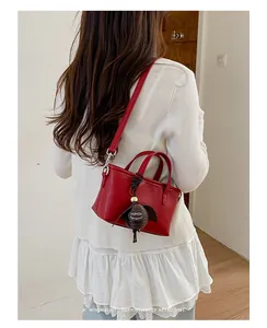 Sac seau rouge minimaliste porté en bandoulière avec une belle breloque décorative.