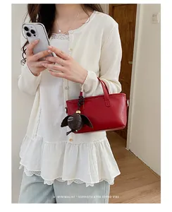 Vue détaillée d'un sac à main rouge minimaliste et chic porté par un mannequin.