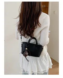 Sac seau noir minimaliste pour femmes, idéal pour le travail, porté à l'épaule.