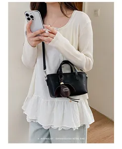 Détail d'un sac seau noir minimaliste muni d'un pendentif marron très élégant