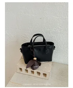 Petit sac cabas noir pour le travail avec breloque mode sur un socle en pierre minimaliste