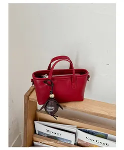 Vue détaillée du sac seau en cuir rouge avec breloque mode sur étagère
