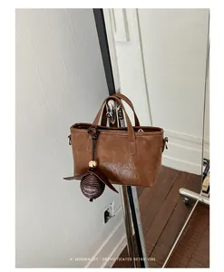 Gros plan d'un petit sac cabas marron de style rétro avec breloque.
