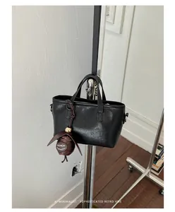Vue détaillée d'un mini sac à main noir minimaliste avec un charmant pendentif marron