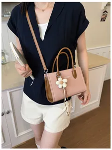Nahaufnahme einer rosa Vintage-Handtasche am Modell mit süßem Blumenanhänger