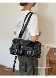 Side view of a black chic underarm bag with rivets and adjustable straps worn by model.