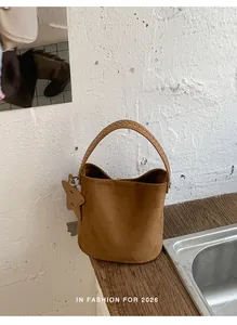 Sac seau en daim marron minimaliste avec une breloque étoile sur un plan de travail