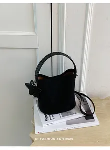 Sac seau noir texture suède avec breloque étoile et poignée tressée sur livres