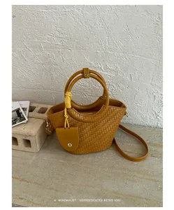Gros plan d'un sac seau tissé jaune avec poignée rétro sur fond de pierre texturée
