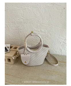 Vue détaillée d'un sac seau tissé crème avec poignée ronde et design rétro élégant