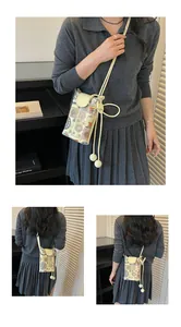 Modèle présentant un petit sac bandoulière brodé de style ethnique avec une lanière