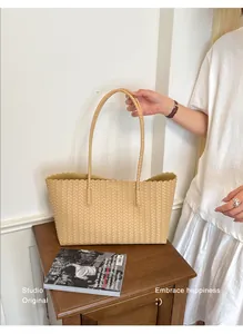 Elegante borsa tote intrecciata beige presentata in un ambiente professionale di studio