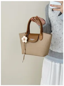 Detail shot of khaki canvas tote bag with brown leather handles and flower charm