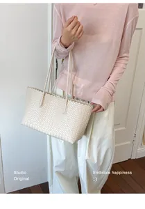 Vista dettagliata di una borsa tote intrecciata crema con bordi ondulati