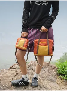 Detailed view of two orange checkered crossbody bags in different sizes held by a model