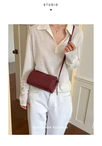 Close-up of a burgundy retro woven barrel crossbody bag styled on a white polo shirt outfit