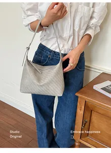 Detailed view of the chic woven texture on a stylish light grey underarm hobo bag