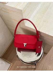 Elegante borsa baguette rossa con pochette coordinata su uno sgabello d'argento