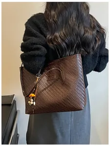 Gros plan détaillé d'un sac cabas rétro tissé marron foncé porté par un mannequin en scène