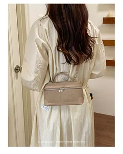 Achteraanzicht van een model met een chique beige getextureerde crossbodytas met zilveren rits