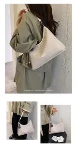 Primo piano di un'elegante borsa sottobraccio intrecciata bianco crema con nappa decorativa.