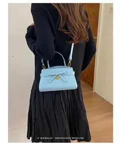 Detailweergave van een blauwe handtas met krokeffect gedragen door een model