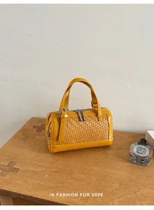 Primo piano di una borsa gialla intrecciata su un tavolo di legno con decorazioni