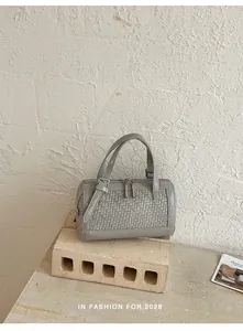 Elegante borsa a mano intrecciata grigia su un piedistallo di pietra in studio