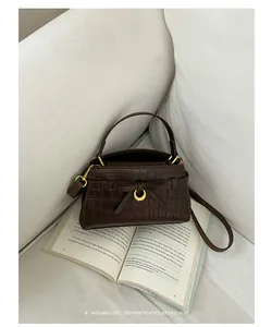 Bruine handtas met steenpatroon op een boek voor een minimalistische retro-vibe.