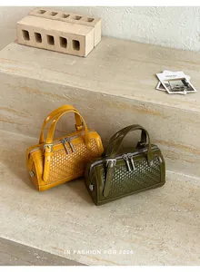 Borse a botte intrecciate in giallo senape e verde oliva su scala in pietra