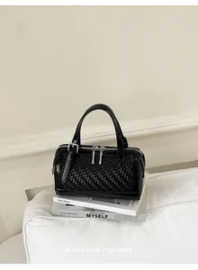 Vista dettagliata di una borsa nera a trama intrecciata su libri in un ambiente minimal