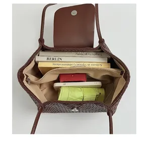 Close-up of the spacious interior of a brown woven tote bag with books and umbrella