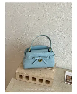 Minimalistische lichtblauwe handtas met steenpatroon en elegant strikdetail in retro.