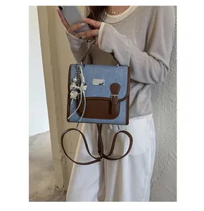 Mochila pequeña de moda en mezclilla y cuero para mujer con colgantes plateados y asa