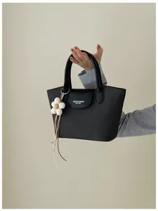 Close-up detail of black retro tote bag with leather flap and a cute white flower charm