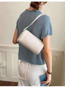 Elegant vintage cream woven cylinder underarm bag presented on a model's shoulder.