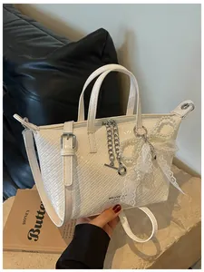 Close-up of a white woven commuter tote bag featuring elegant pearl and lace charms