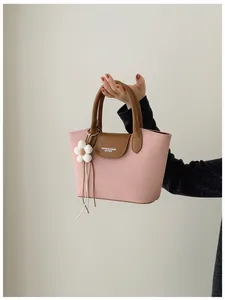 Close-up of retro pink fabric handbag with brown leather flap and flower charm.