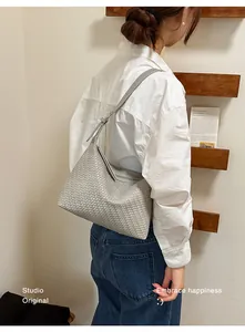 Elegant gray woven underarm bag detail shown worn by a model in a lifestyle setting