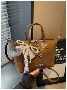 Detail showing a stylish brown woven tote bag featuring an elegant pearl and lace bow charm detail