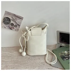 Mini sac seau blanc minimaliste avec breloques sphériques dans un cadre de vie.