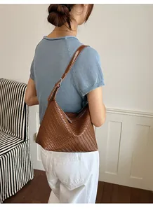 Rear view of brown woven underarm bag showing texture and leather strap details.