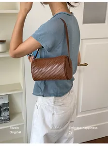 Stylish model carrying a vintage brown woven cylinder underarm bag for women lifestyle view