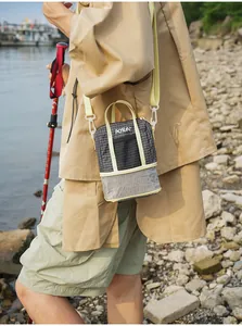 Small grid pattern crossbody tote bag worn by a model in a natural outdoor setting