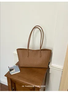 Vista dettagliata di una borsa a tracolla intrecciata marrone su un comodino in legno vintage.