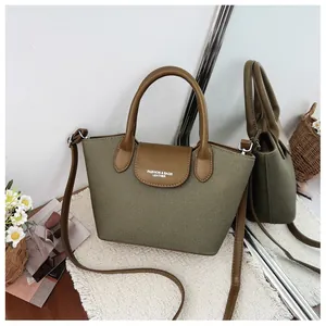 Detail of olive green canvas handbag with brown leather flap and adjustable strap