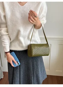 Retro olive green woven cylinder bag worn as a shoulder underarm purse by model
