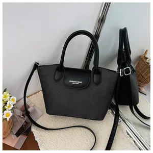Detailed view of a black textured handbag featuring a leather flap and handles.