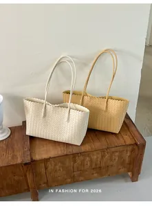 Dettaglio di borse tote intrecciate in bianco e marrone su una panca di legno.