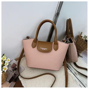 Detailed close-up of pink and brown retro handbag featuring leather flap and logo text